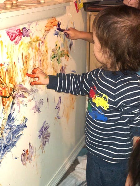 Child finger painting on a wall