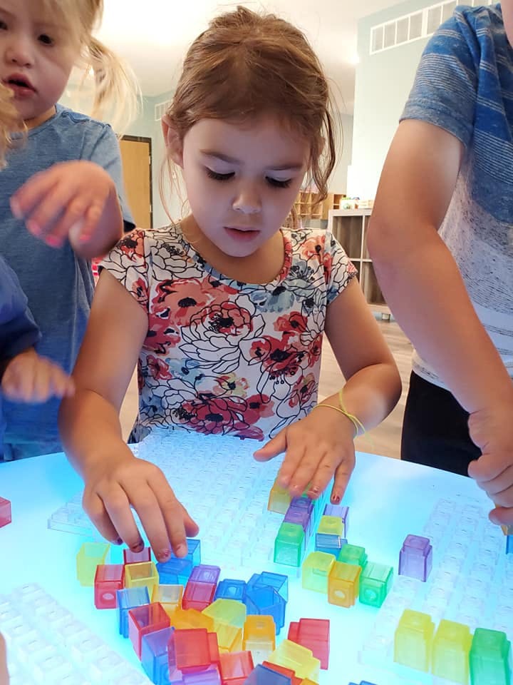 Child playing with colorful translucent blocks on a light table