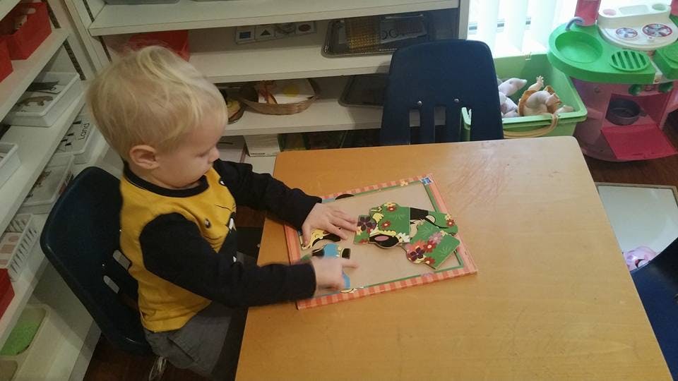 Child playing with a puzzle at a table