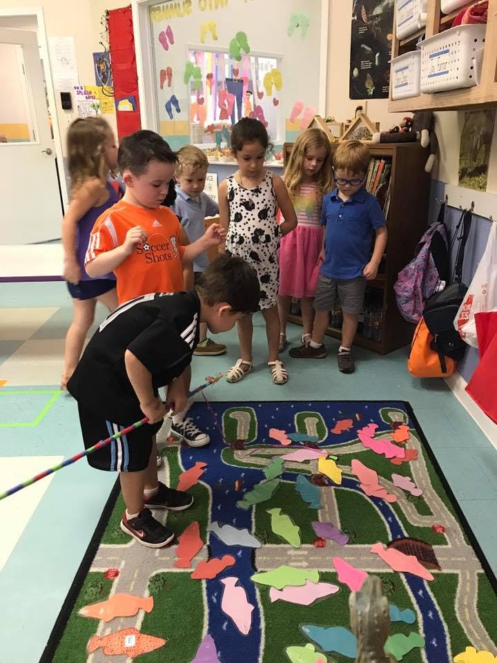 Children playing a fishing game on a rug