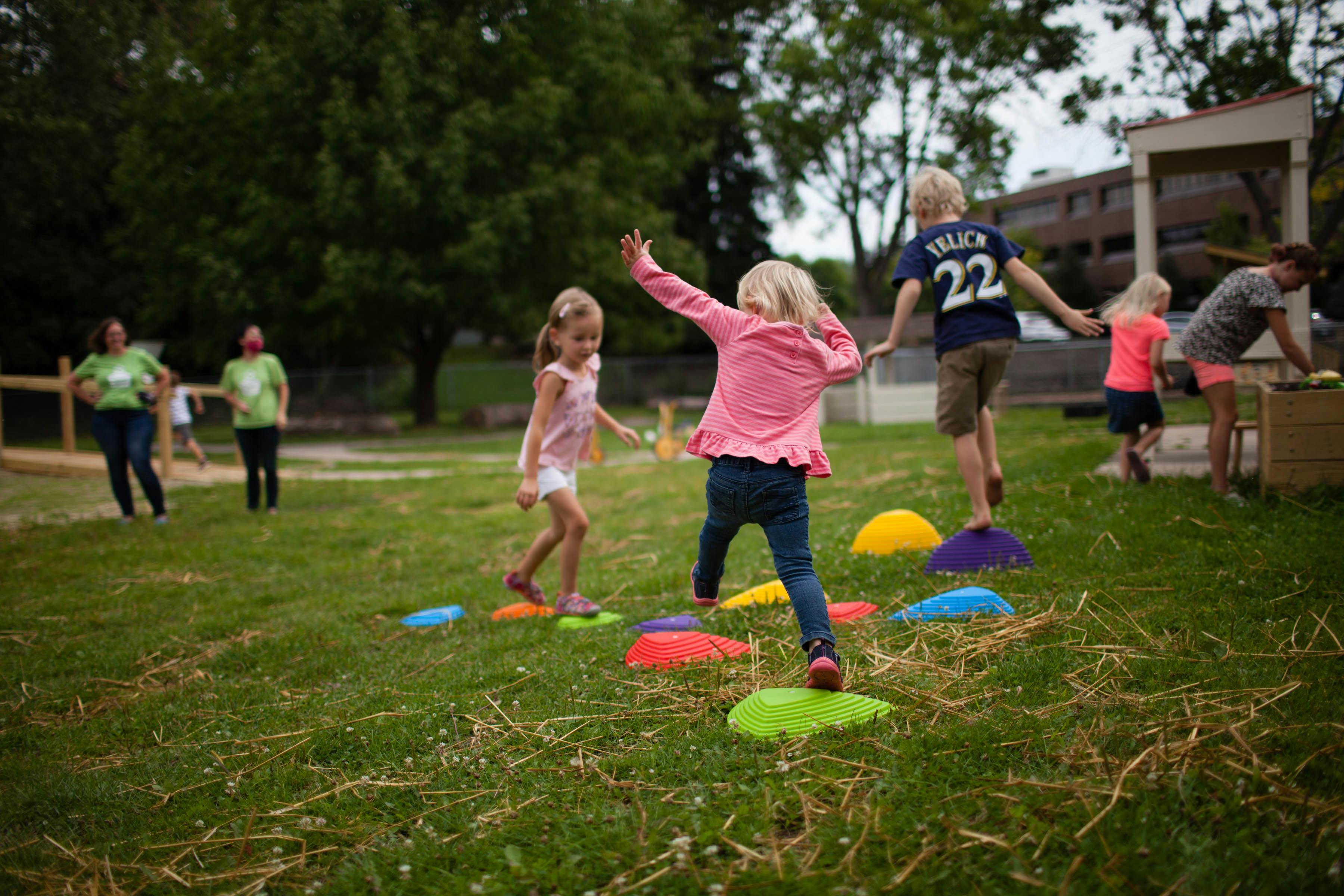 Children playing on colorful stepping stones in a grassy area
