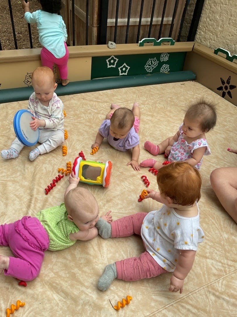 Multiple babies playing with toys on a mat