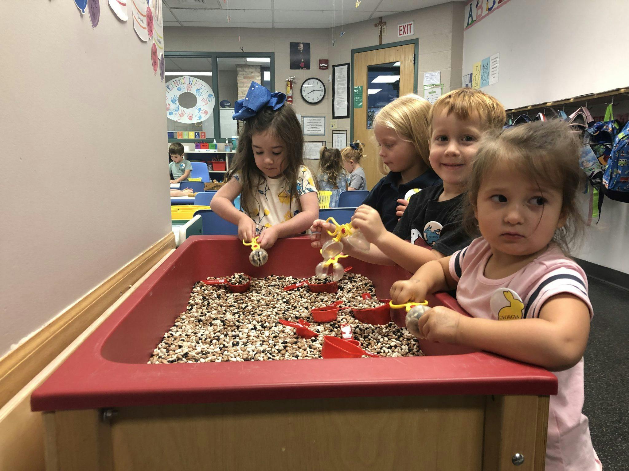 Children playing in a sensory bin with scoops and small objects