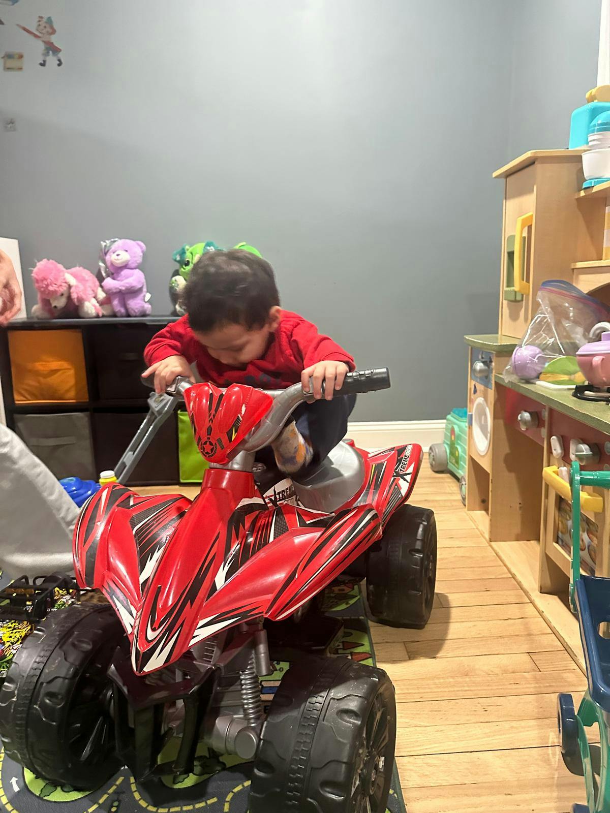 Child sitting on a red toy ATV
