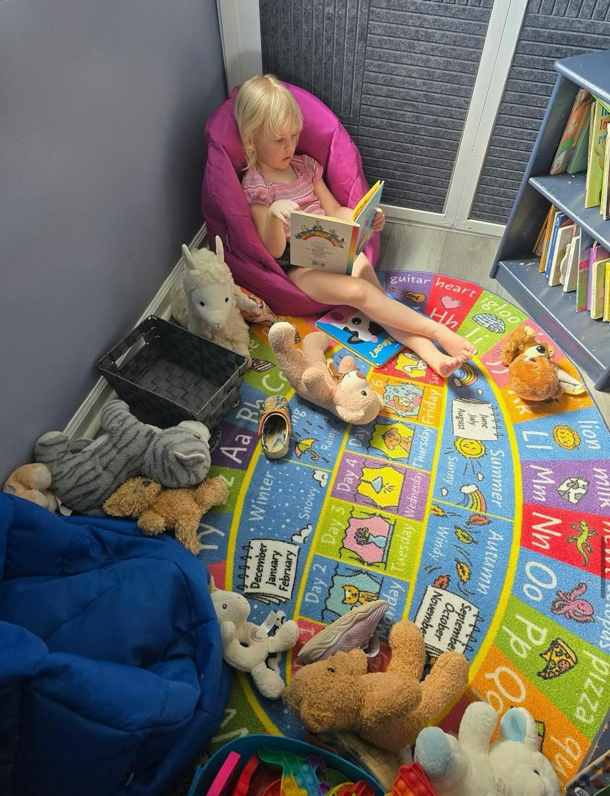 Child sitting in a beanbag chair reading a book on a colorful rug