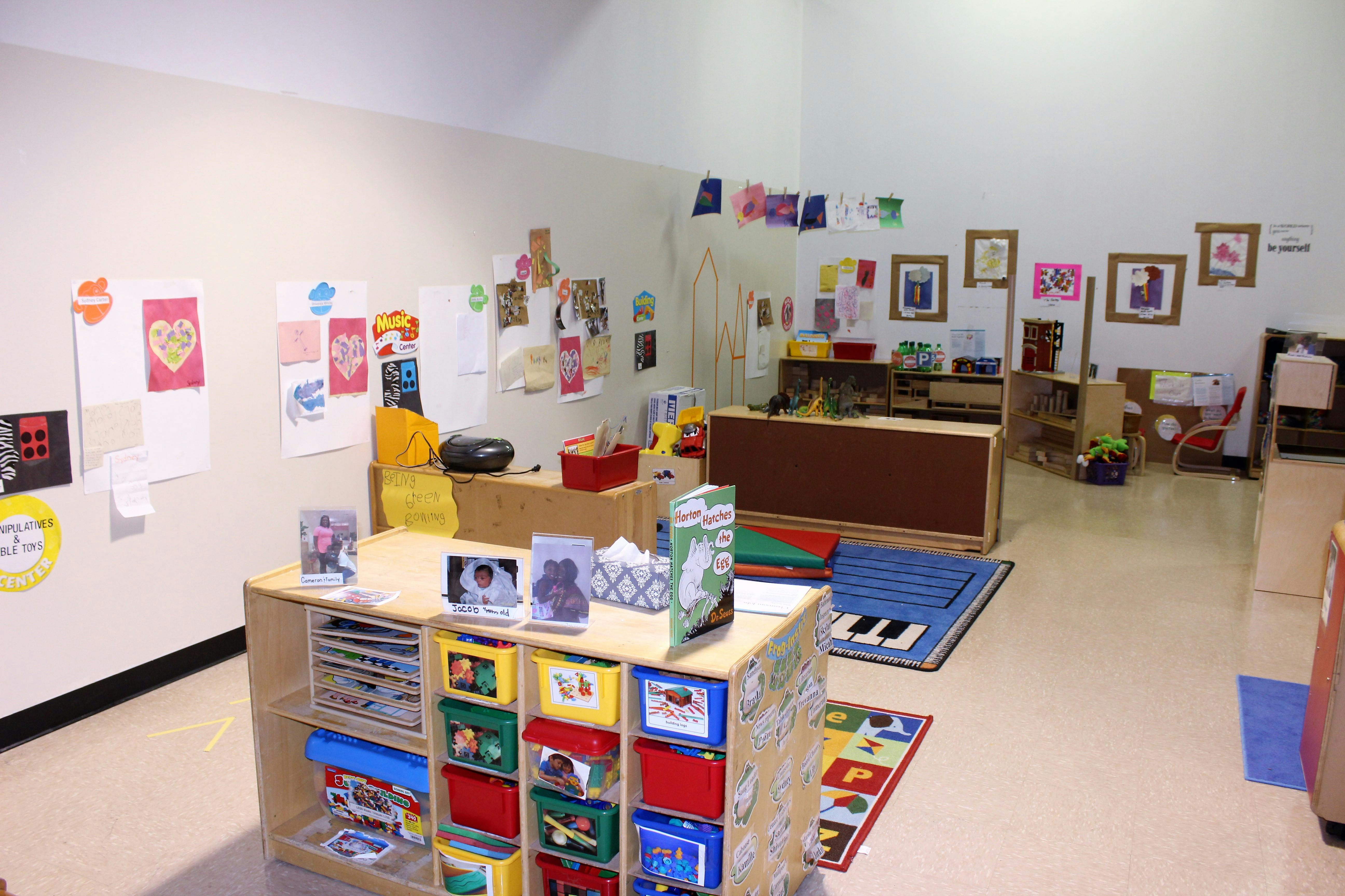 Classroom with children's artwork on walls and storage shelves with colorful bins
