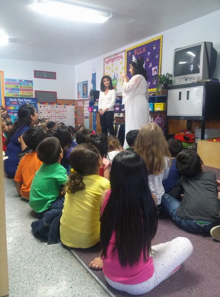 Two people standing in front of a group of children sitting on the floor