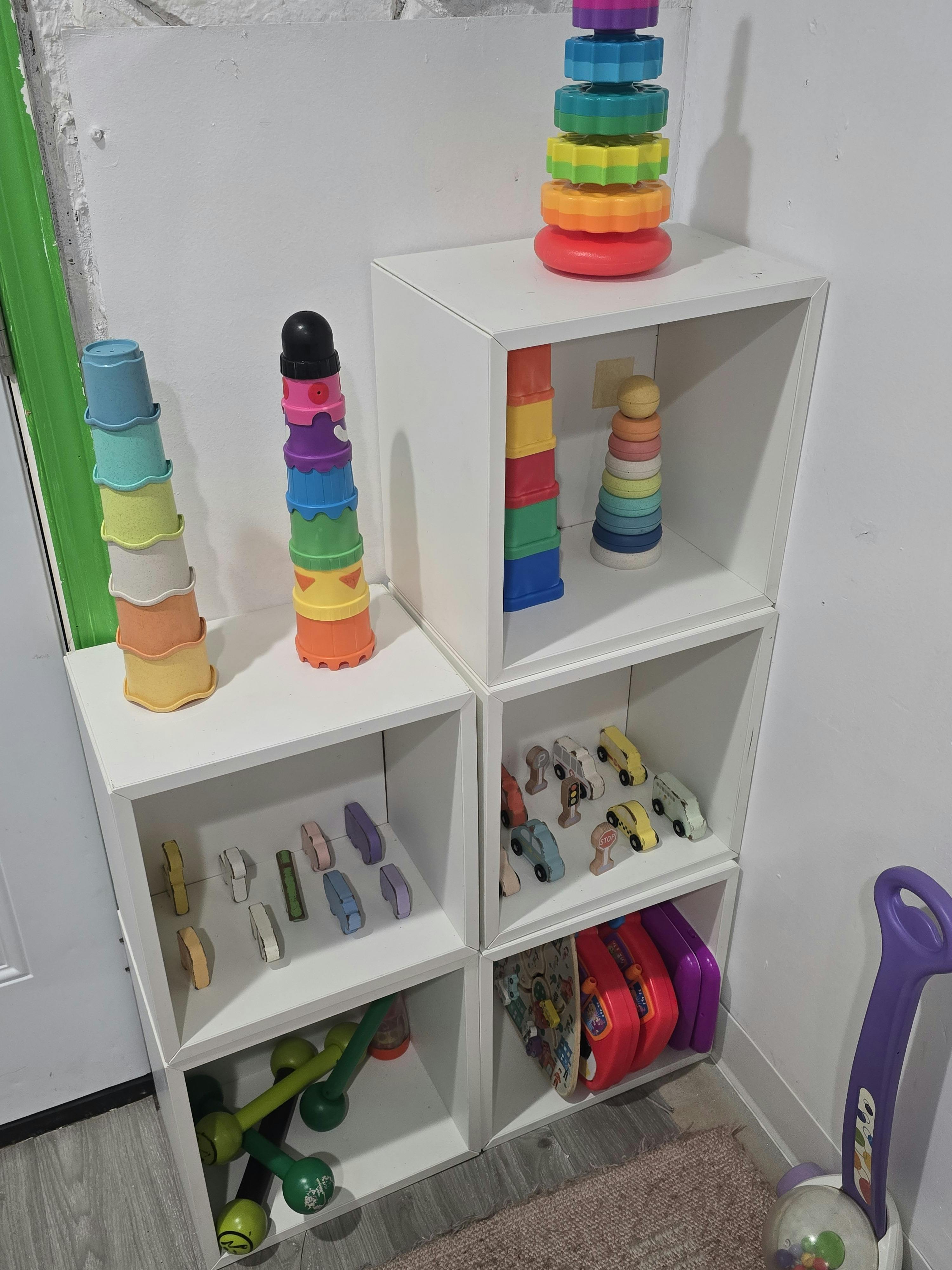 White shelves with colorful stacking toys and small cars
