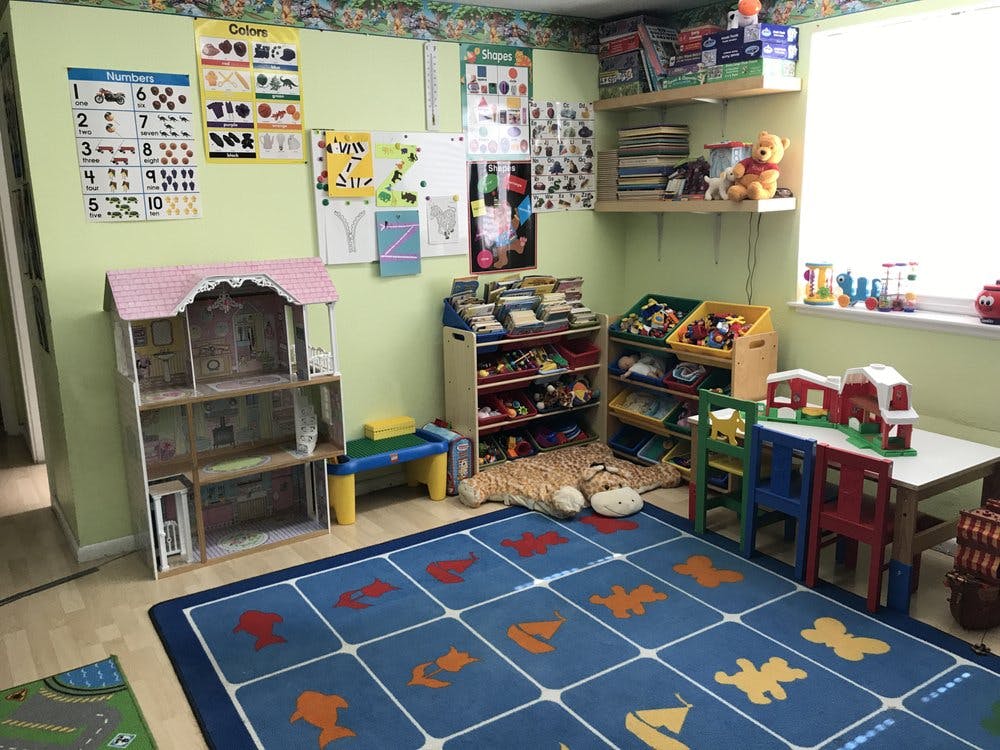 Playroom with a dollhouse, toy shelves, and a blue rug with animal shapes