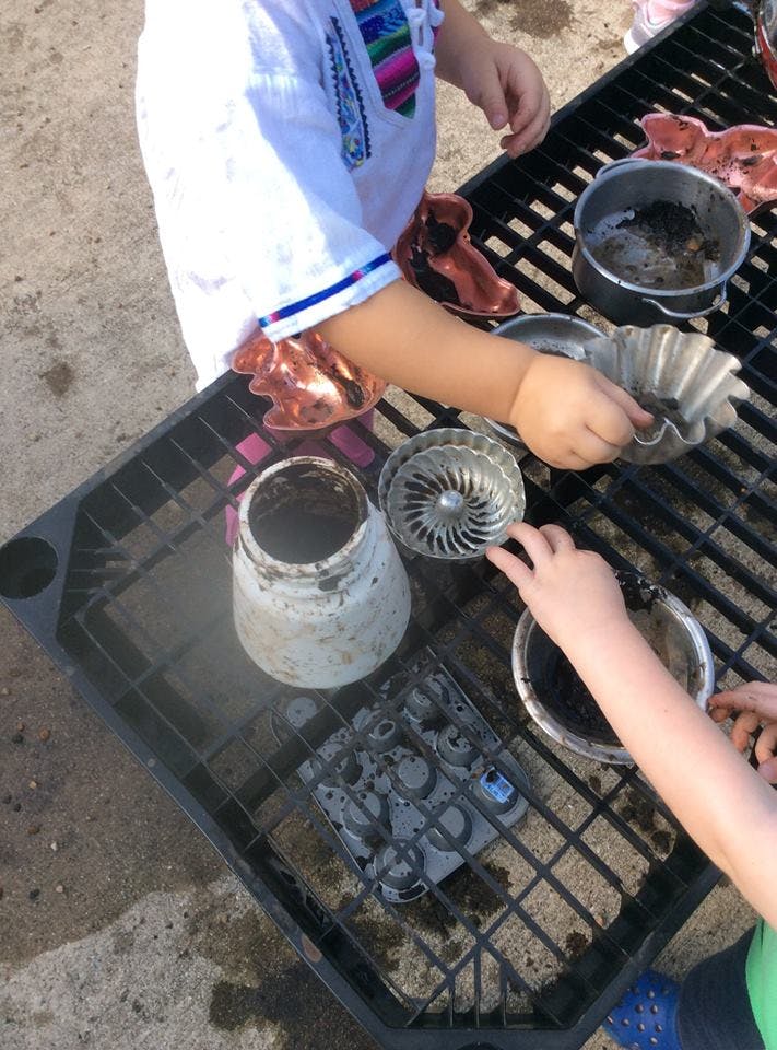 Children playing with various containers on a grate