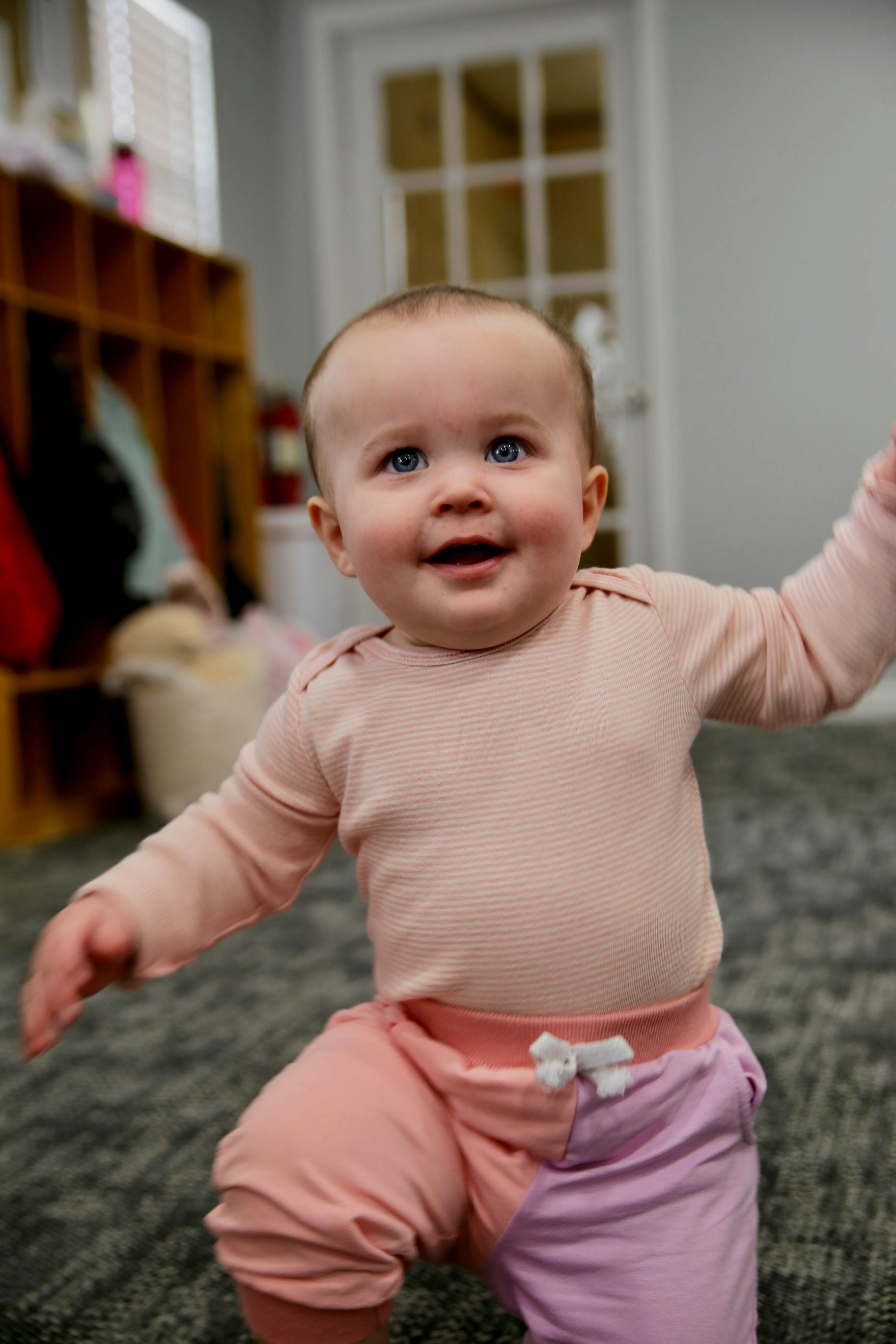 Child in pink and purple pants crawling on a rug