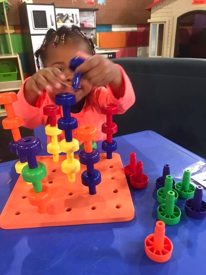 Child playing with colorful stacking toys on a blue table