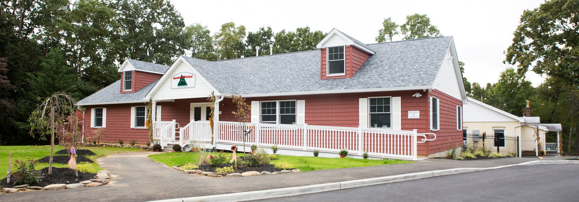 Red house with white trim and a white picket fence