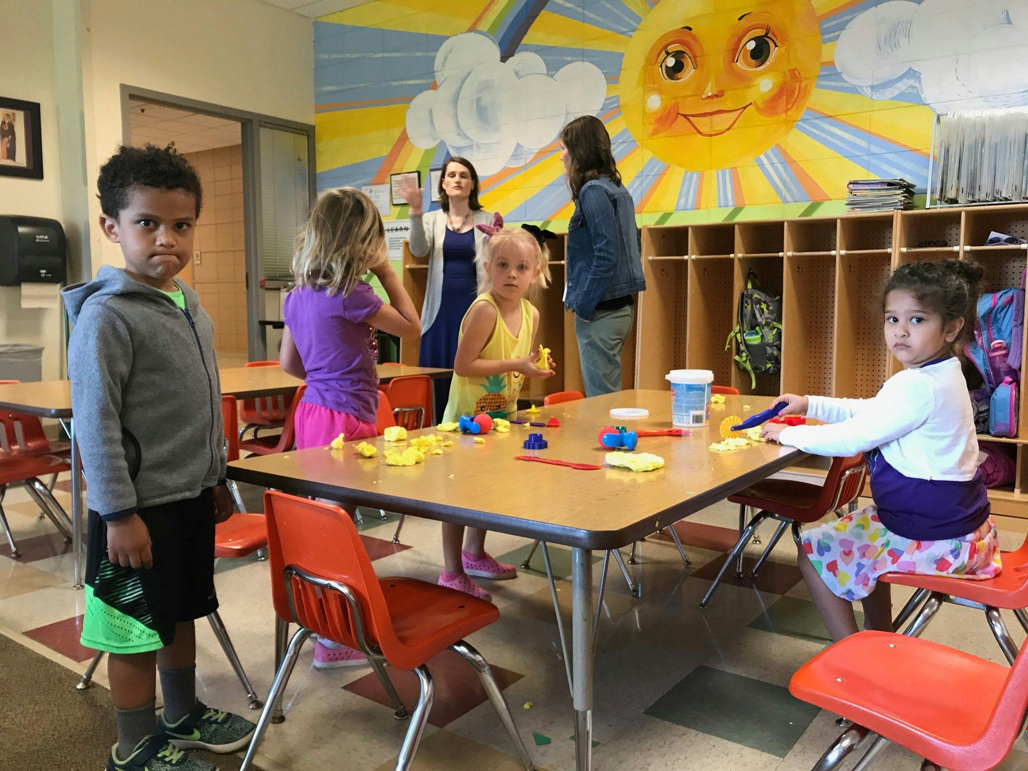 Children playing with toys at tables in a classroom
