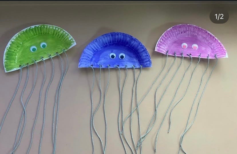 Crafts of jellyfish made from paper plates, googly eyes, and string