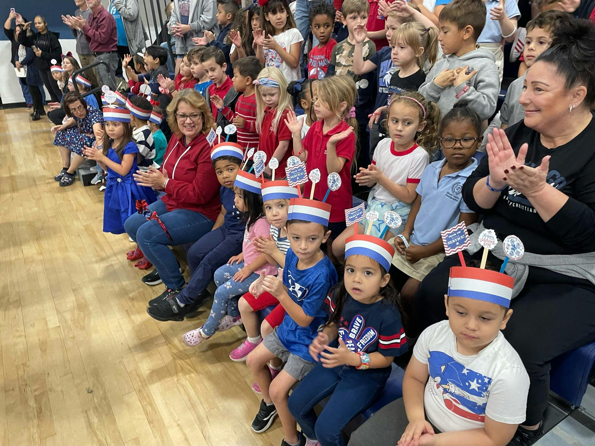 Adults and children in a group, many wearing red, white, and blue hats
