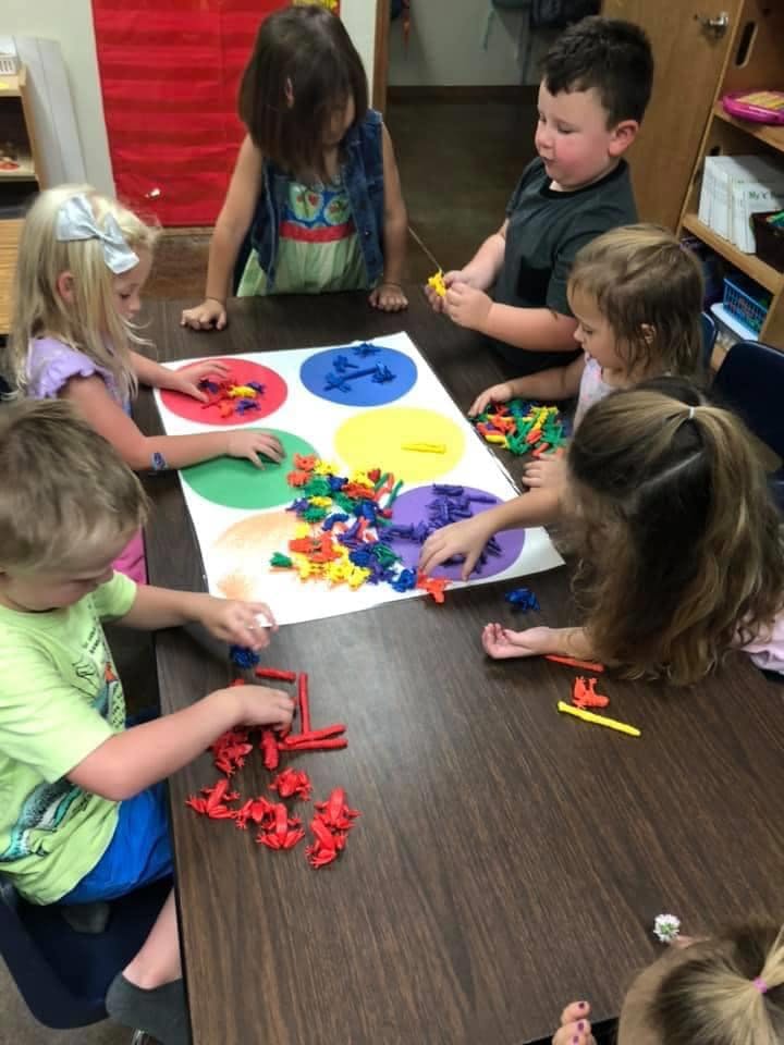 Children playing with colorful shapes on a table