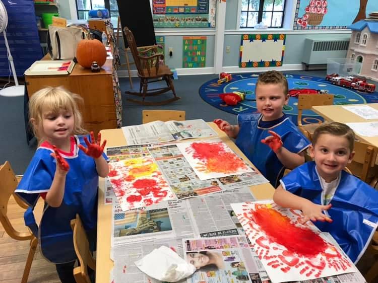 Three children finger painting at a table