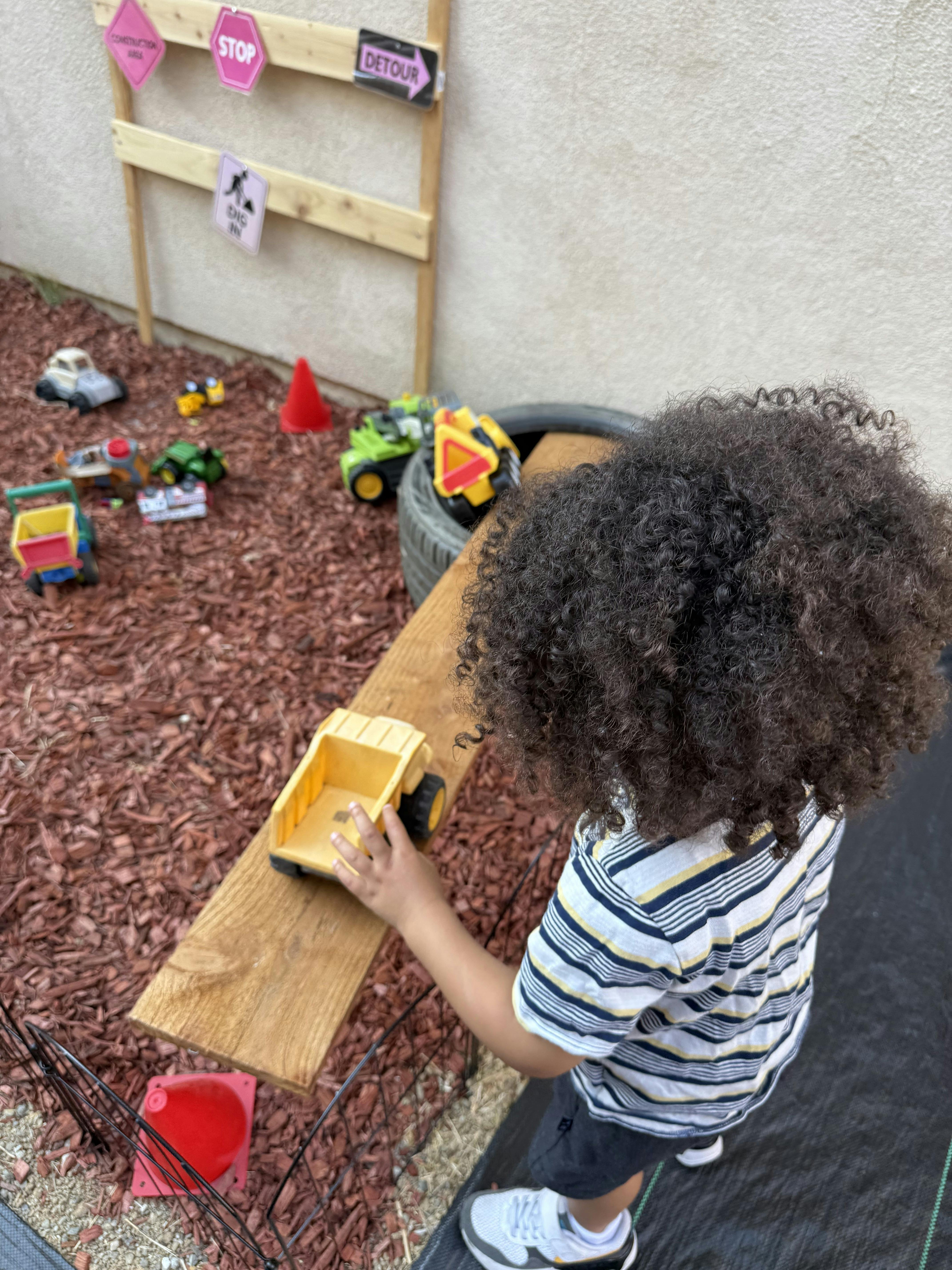 Child playing with a yellow toy dump truck