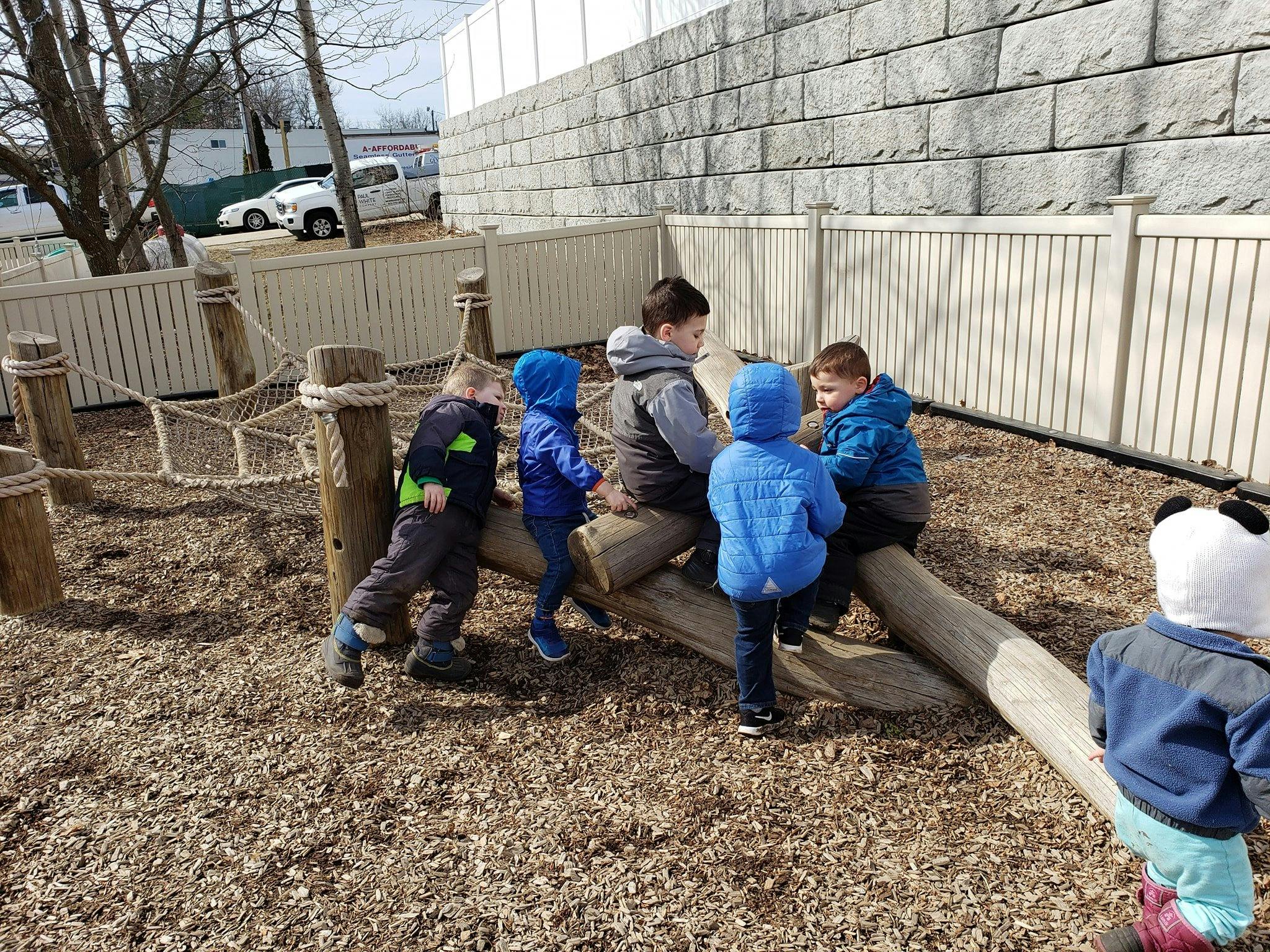 Children playing on wooden logs outdoors