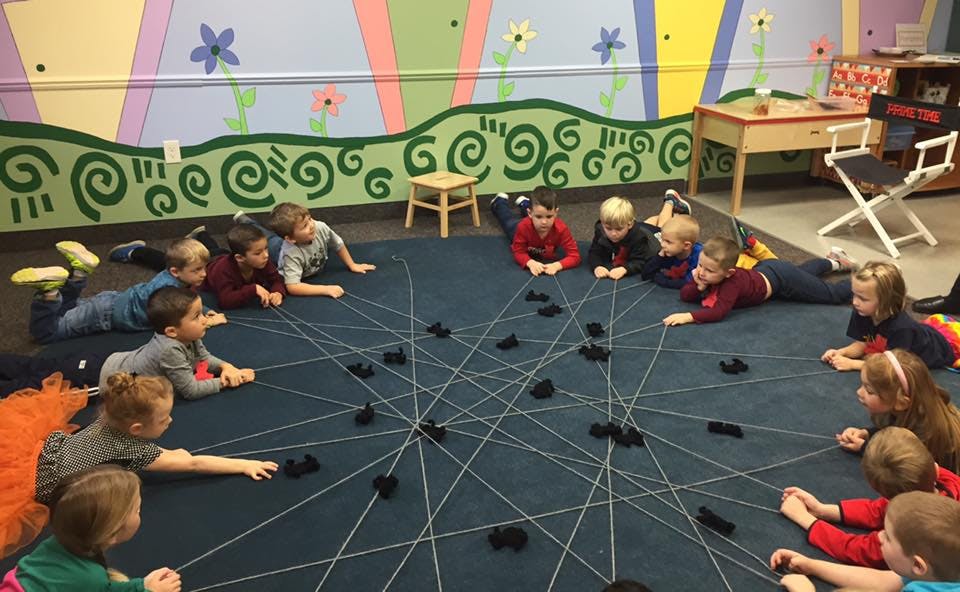 Children lying on a rug with string and blocks