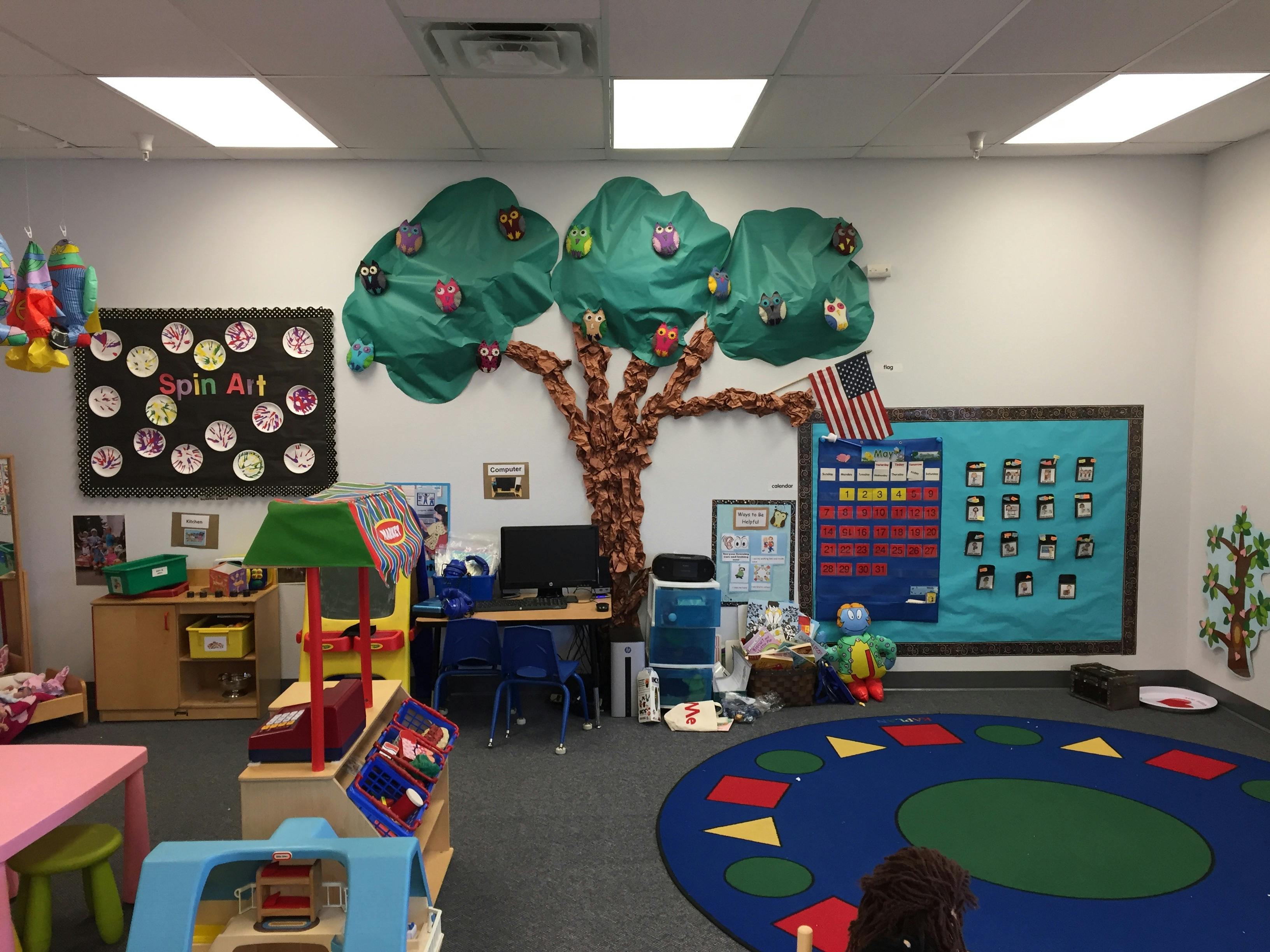 Classroom with a tree decoration on the wall and a blue rug with shapes