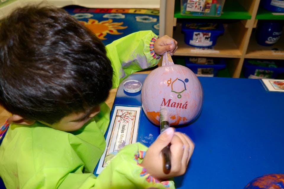 Child painting a pumpkin on a blue table