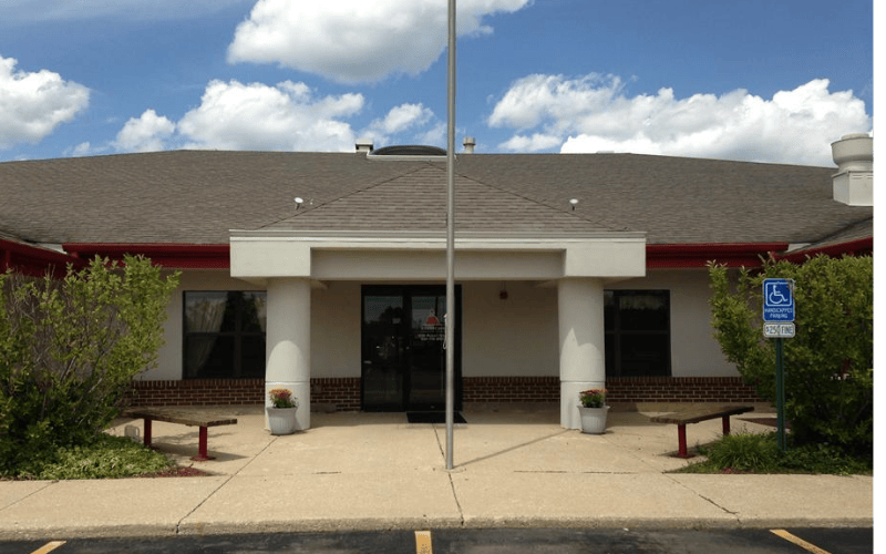 Entrance to a building with a pole, benches, and a handicapped parking sign