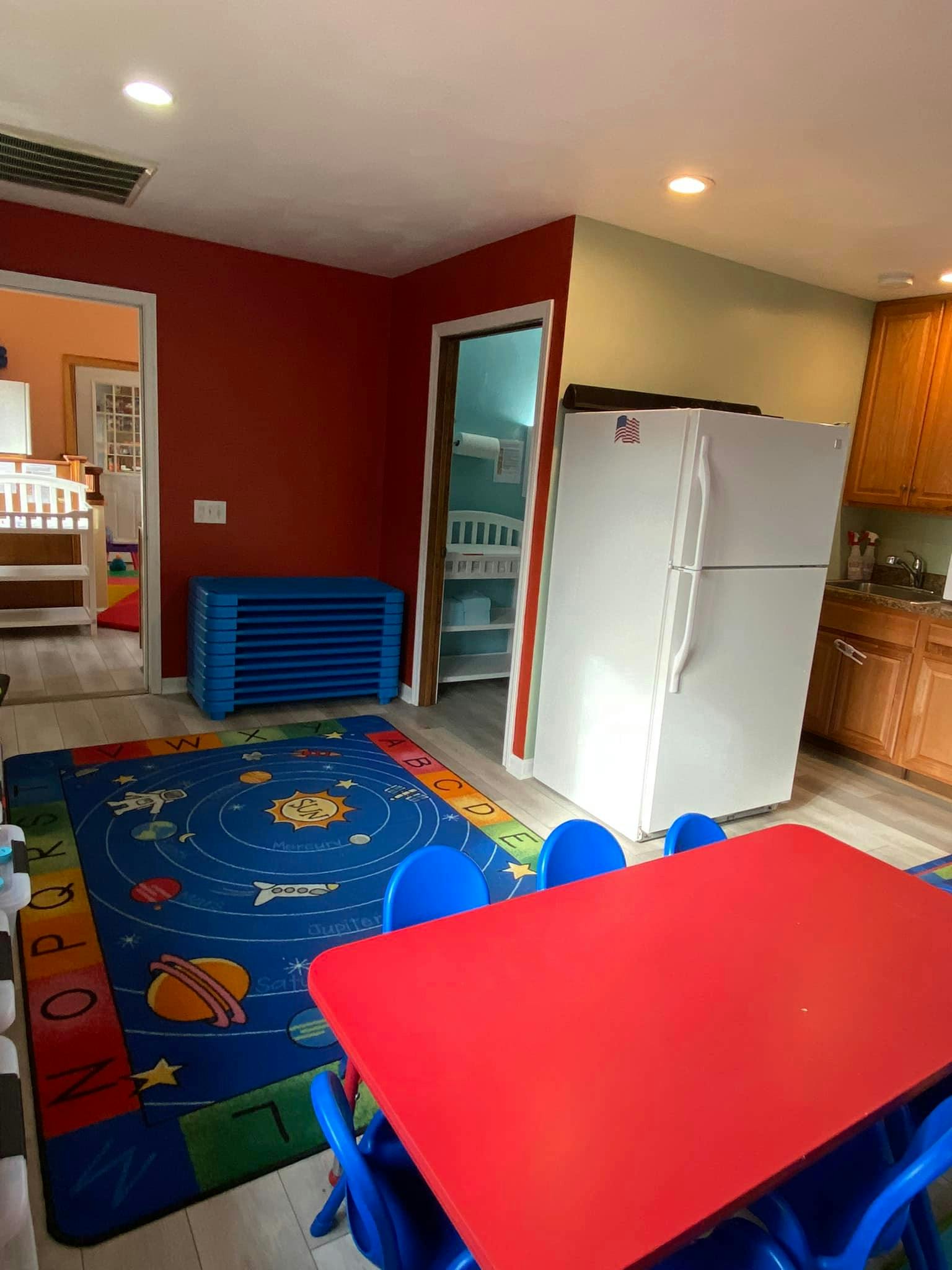 Playroom with a red table, blue chairs, and a space-themed rug