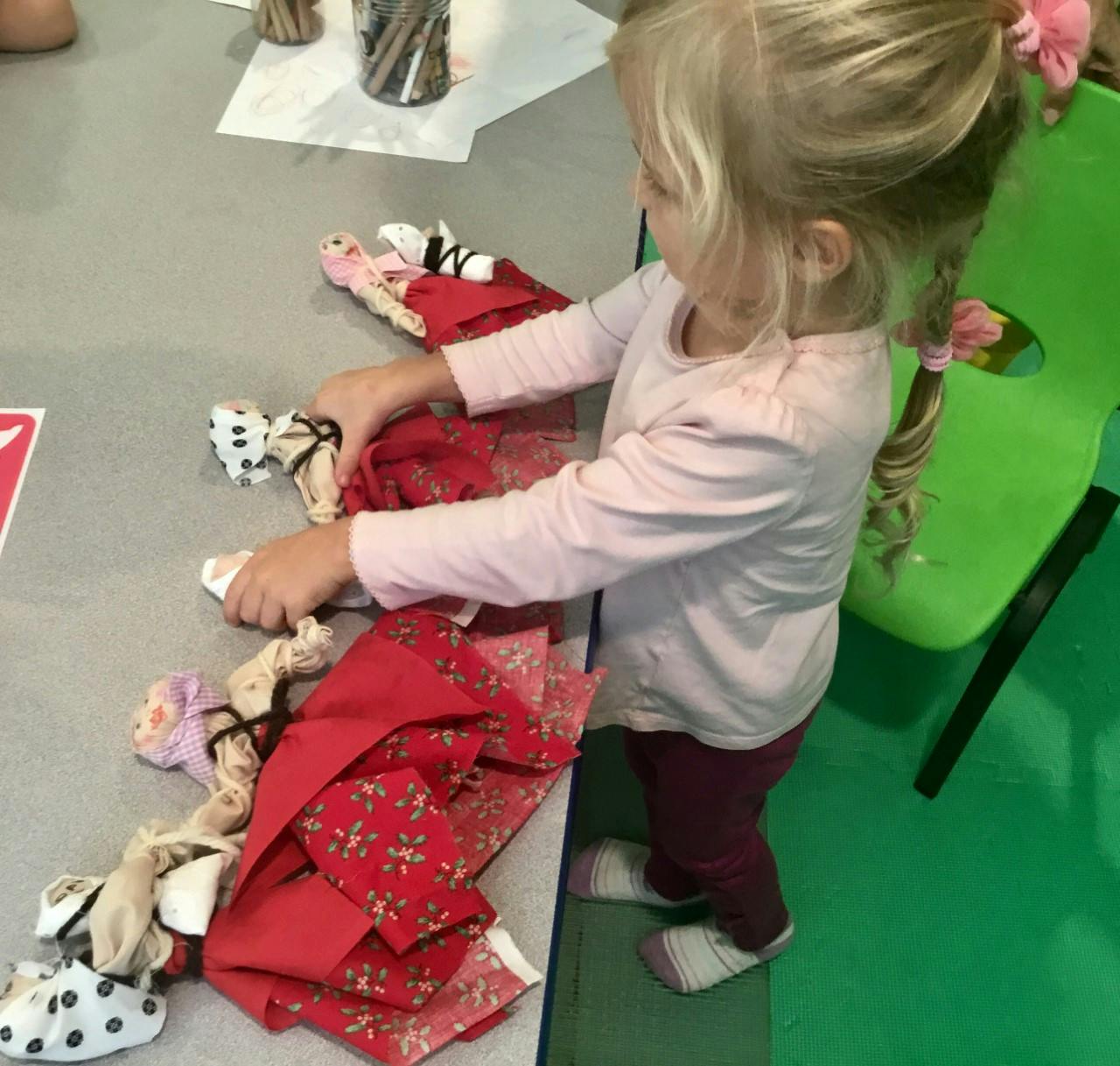 Child playing with fabric dolls on a table