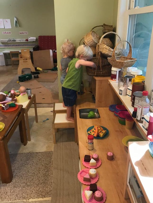 Two children looking into a basket in a classroom