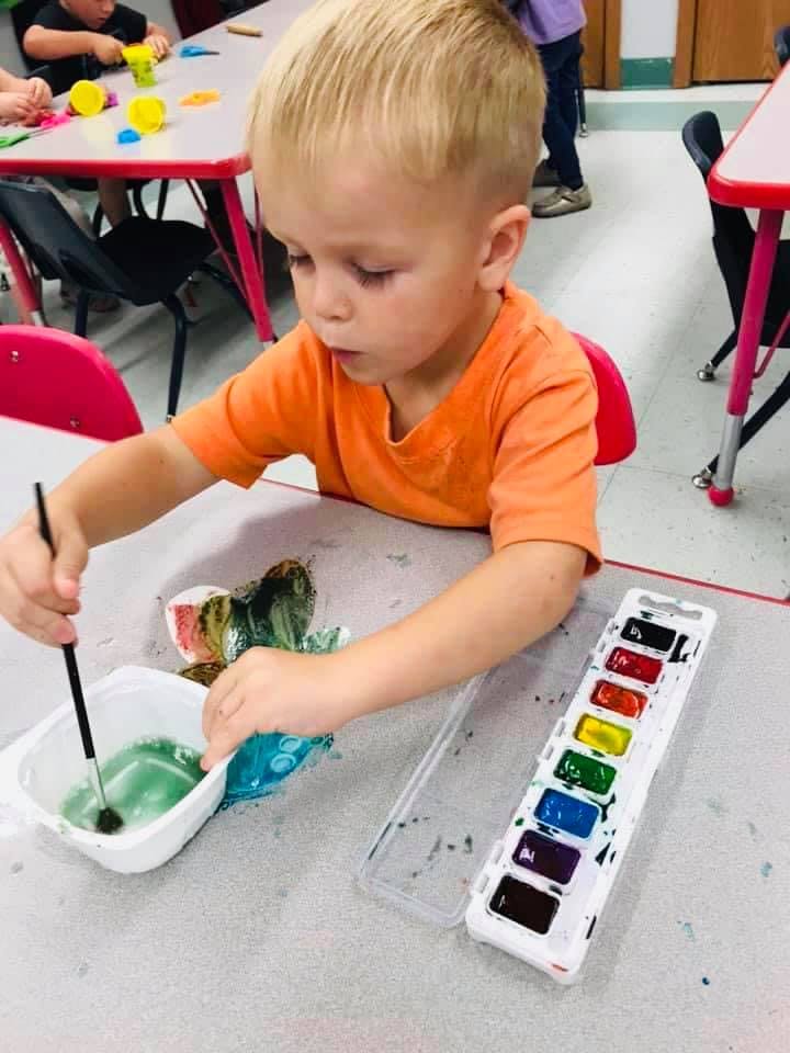 Child painting with watercolors in a classroom