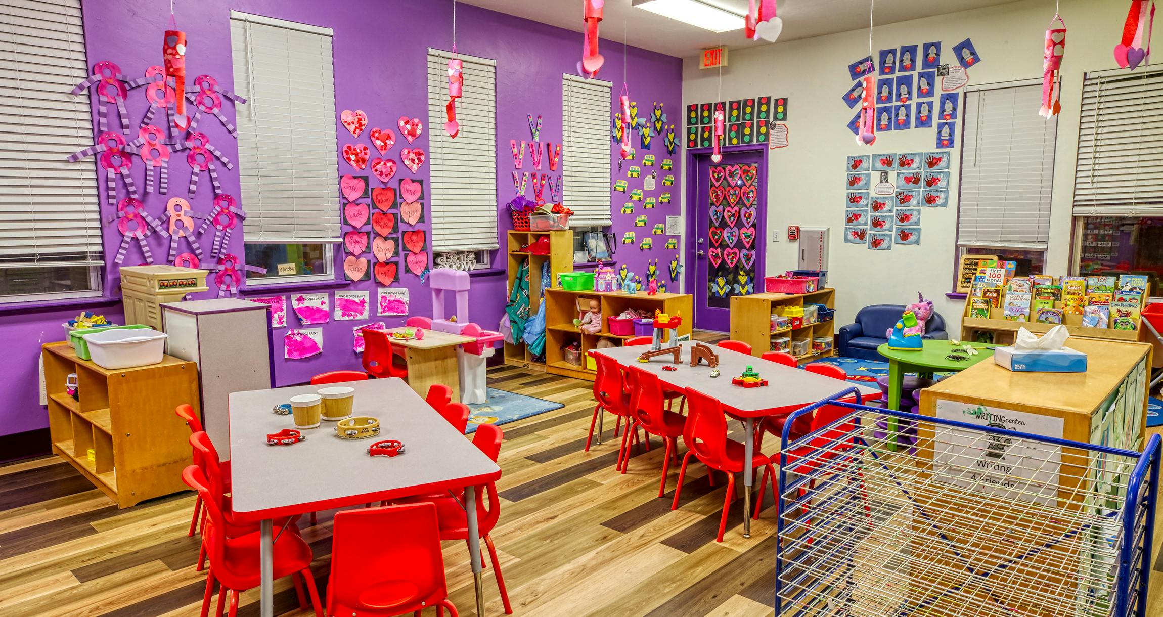 Classroom with purple walls, red tables and chairs, and colorful decorations