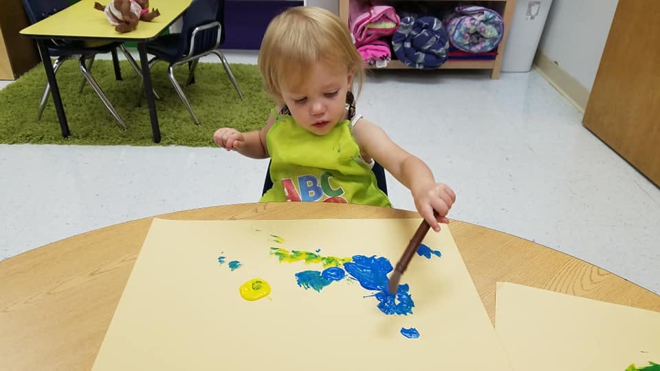 Child painting on paper with a brush