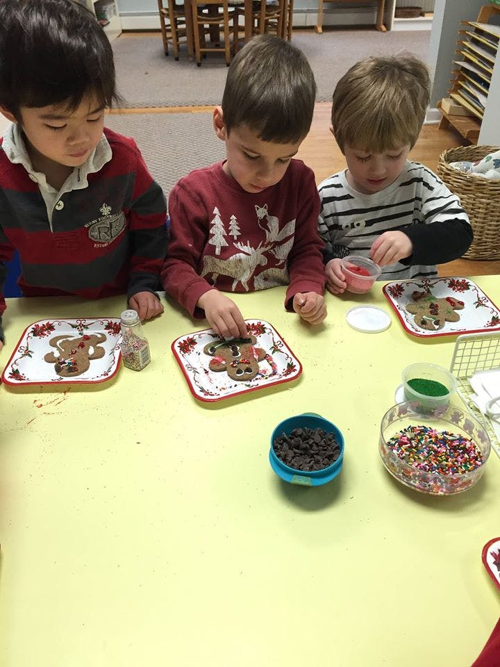 Three children decorating gingerbread cookies at a table