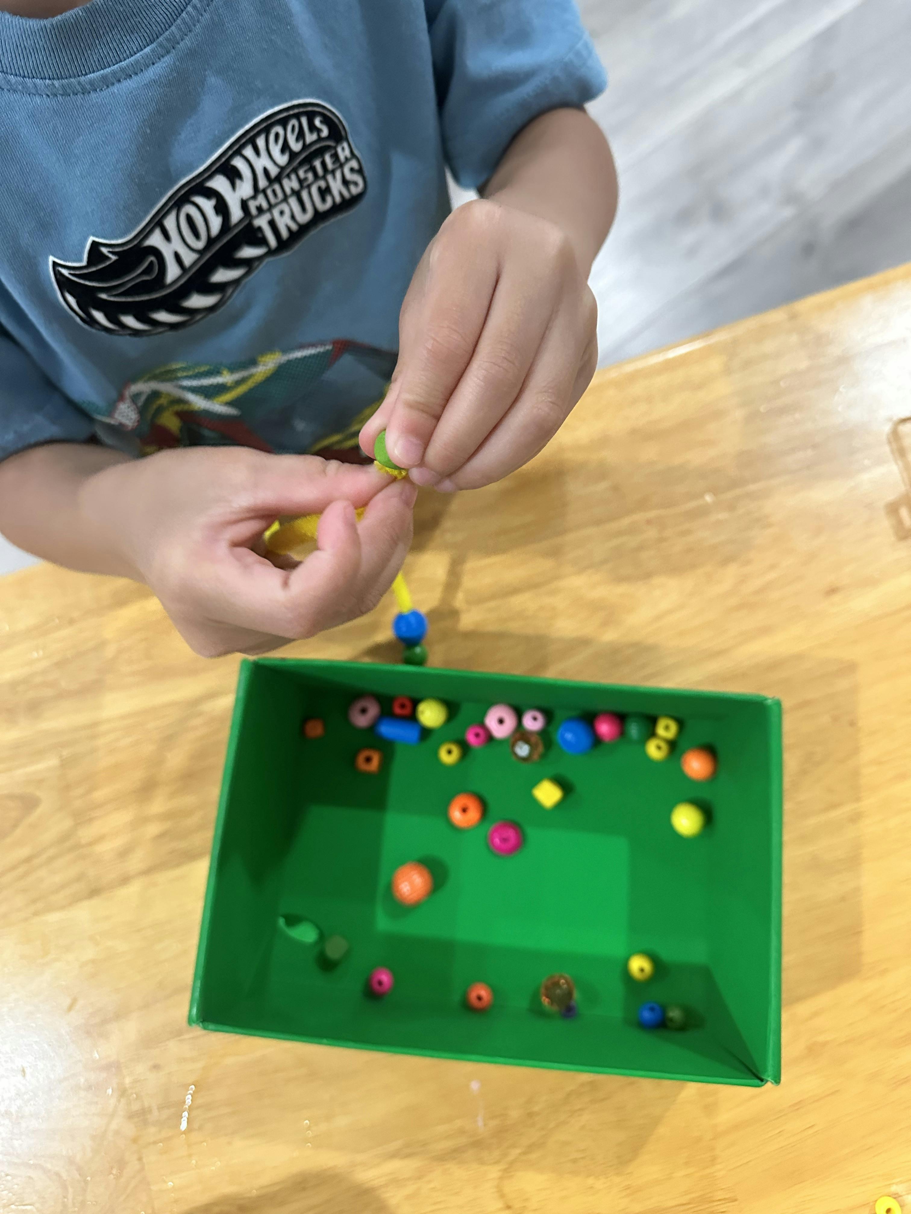 Child threading small beads onto a string