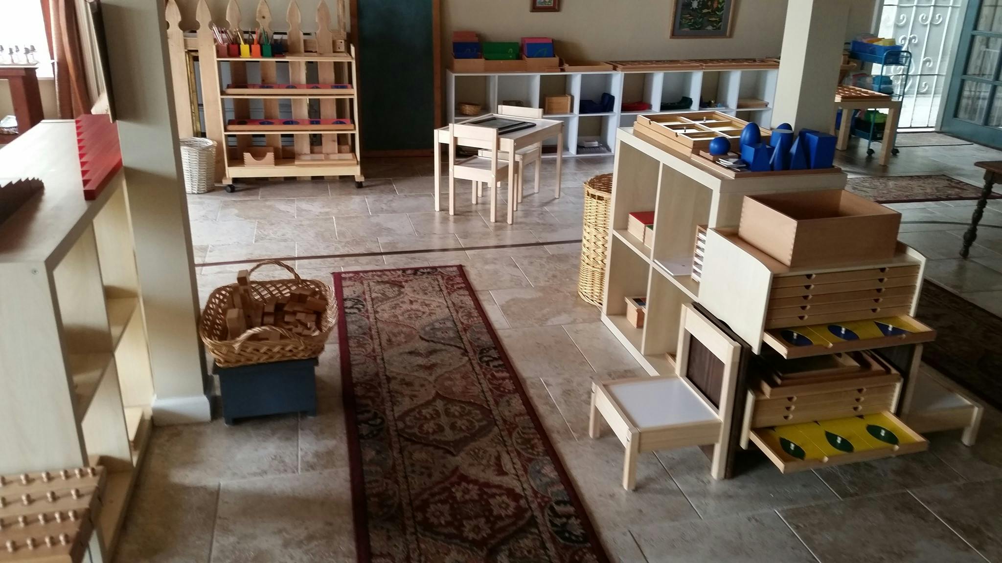 Classroom with wooden shelves, tables, and a rug