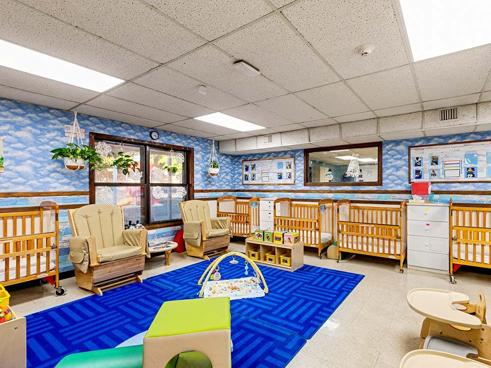 Baby nursery room with cribs, two rocking chairs, and play mats