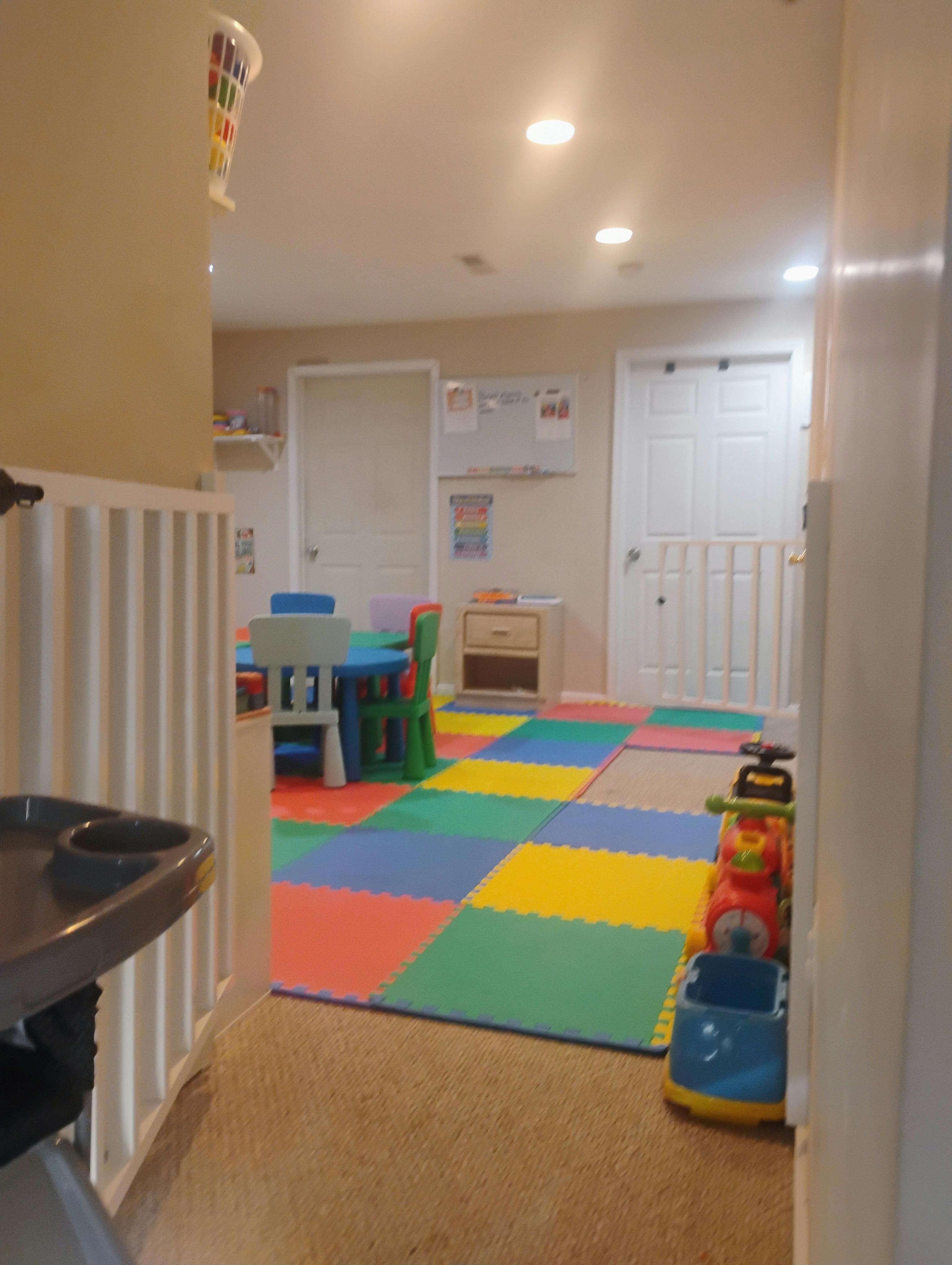 Playroom with colorful foam floor tiles, a child's table and chairs, and toys