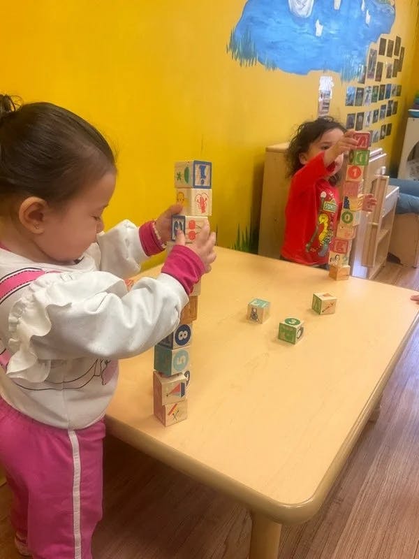 Two children playing with blocks at a table in a classroom