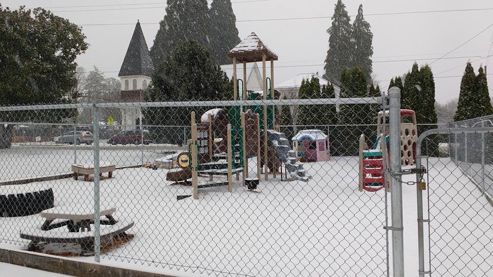 Snow-covered playground with climbing structure and picnic table