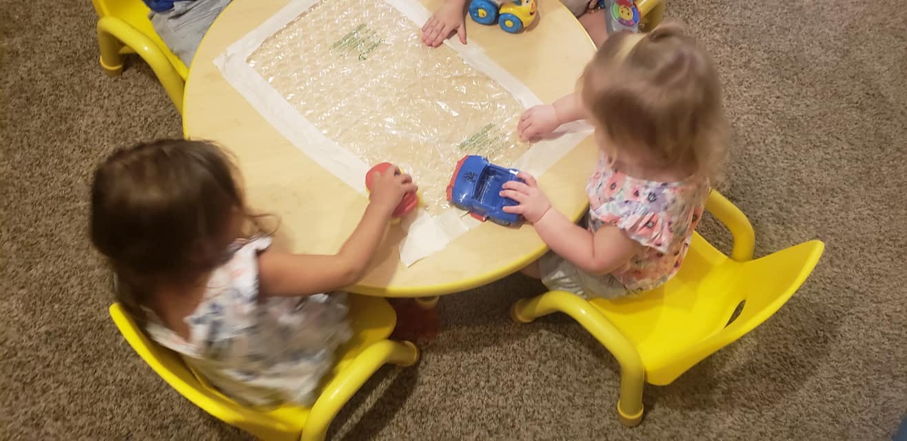Two children playing with toys at a small round table