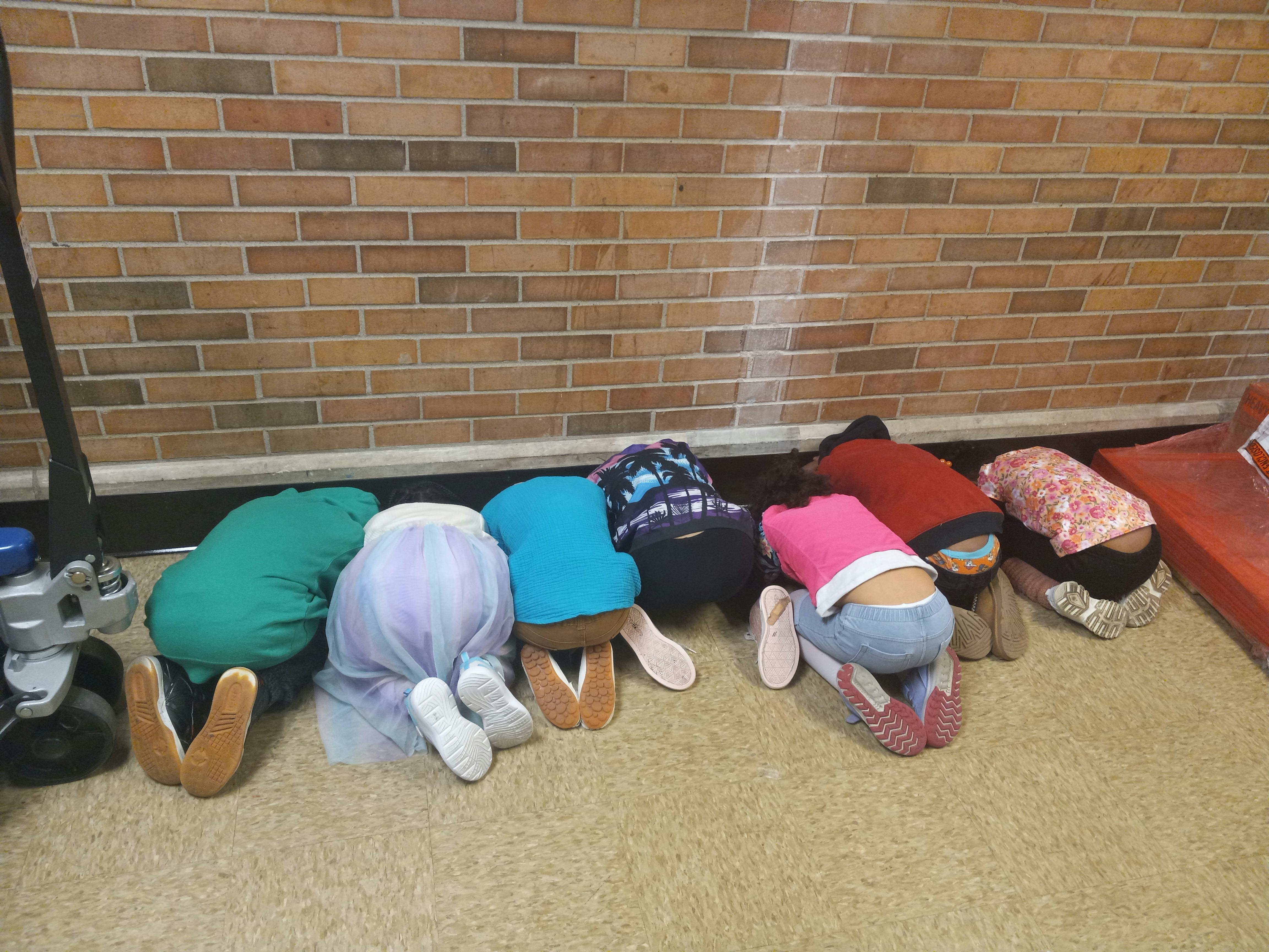 Multiple children kneeling on the floor with their heads down