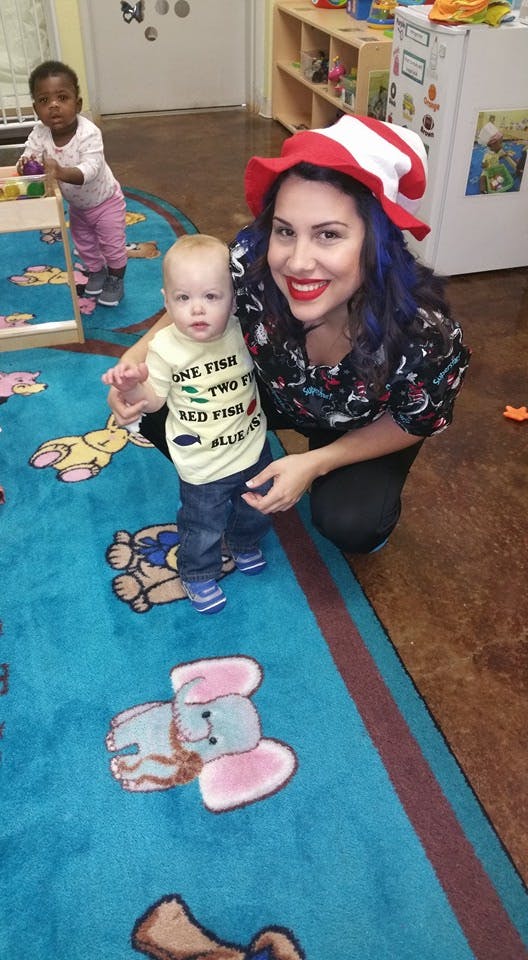 Person in red and white hat with two children in a classroom