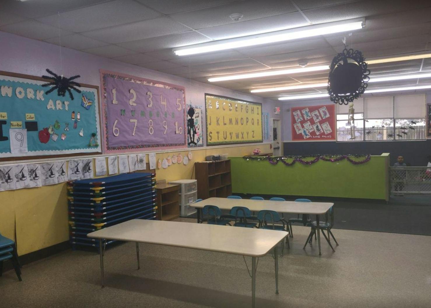 Empty classroom with tables, chairs, and bulletin boards