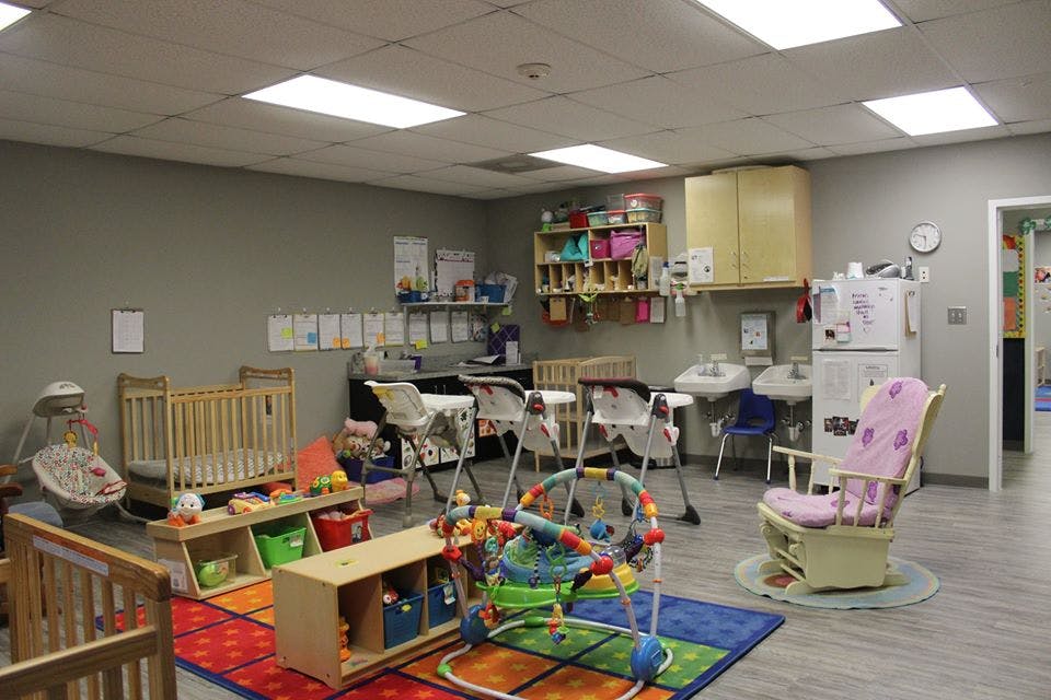 Daycare room with cribs, high chairs, and play mats