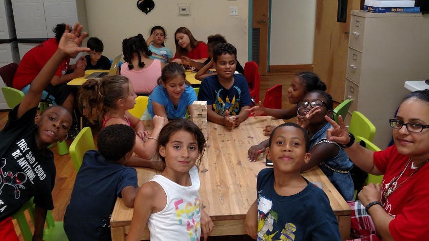 Group of children and adults gathered around tables in a room