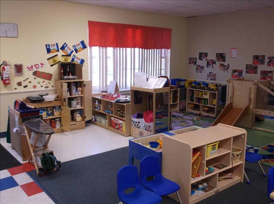 A classroom with shelving units, play areas, and a small slide