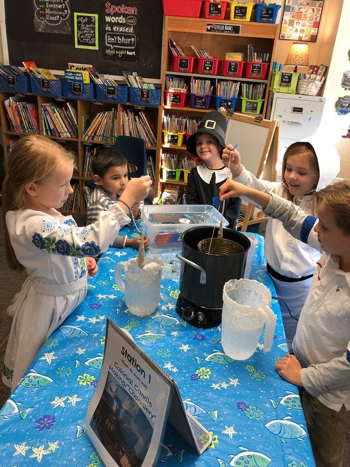 Children gathered around a table with a pot and other items