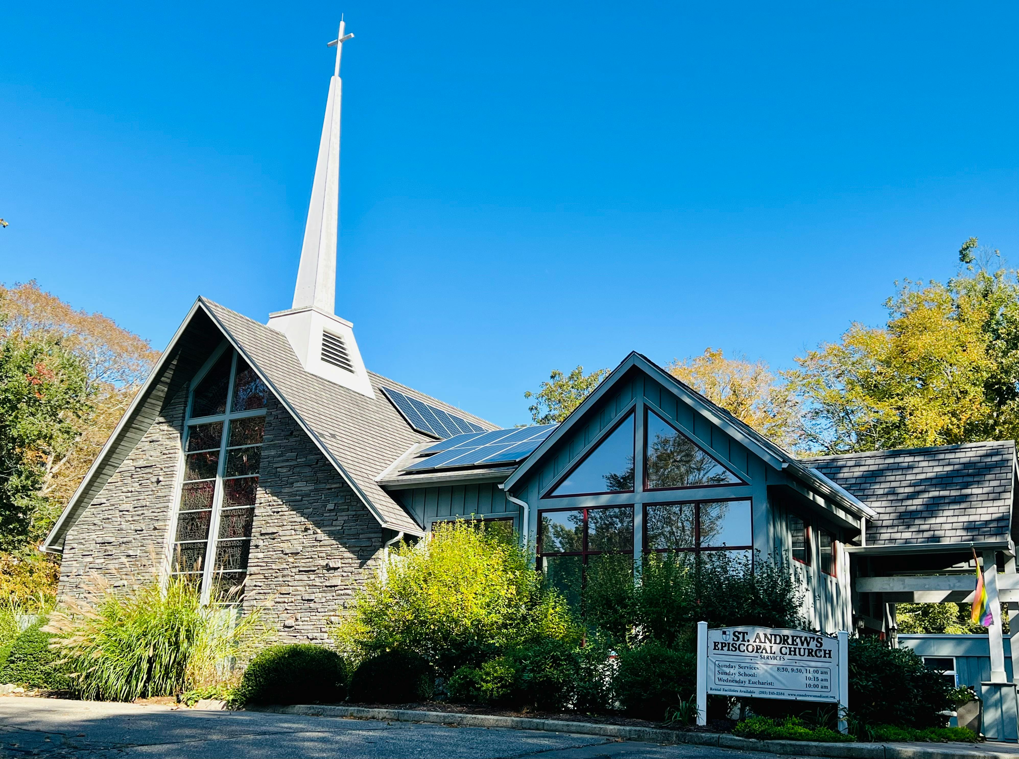 Church building with a tall white steeple and a sign in front